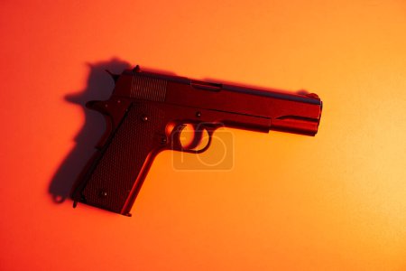 Photo for Big black gun pistol on orange background. - Royalty Free Image