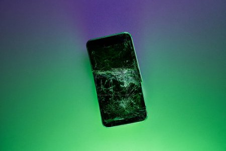 Photo for Mobile smartphone with broken screen on green background. - Royalty Free Image
