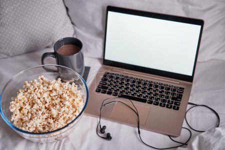 Photo for Watching movie at home. Popcorn in bowl and laptop computer in bed. Entertainment concept. - Royalty Free Image