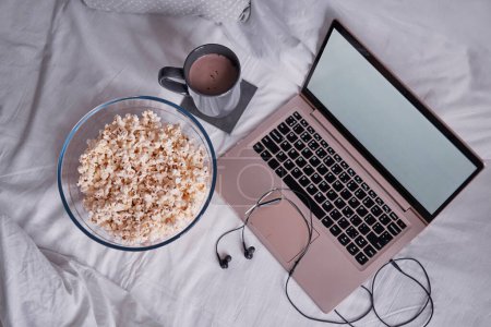 Photo for Watching movie at home. Popcorn in bowl and laptop computer in bed. Entertainment concept. - Royalty Free Image