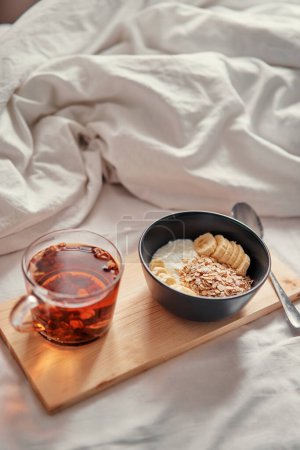 Photo for Good morning. Breakfast in bed. Bowl of granola and cup of hot tea. - Royalty Free Image