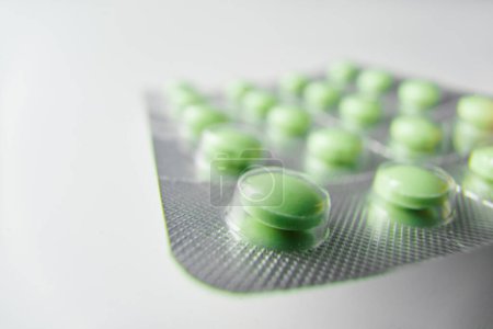 Téléchargez les photos : Des pilules vertes. Plaquette thermoformée avec des pilules sur fond blanc. - en image libre de droit