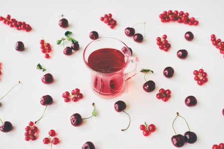 Téléchargez les photos : Coupe en verre de thé aux fruits sur fond blanc avec des baies rouges. - en image libre de droit