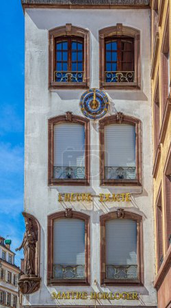 Foto de STRASBOURG, ALSACE, FRANCIA - Edificio histórico en el casco antiguo, situado en la Plaza Gutenberg, con la insignia medieval del reloj, la hora exacta y el maestro relojero. - Imagen libre de derechos