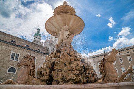 Photo for SALZBURG, AUSTRIA - APRIL 27, 2023: Detail of the medieval Residenzbrunnen, located in Residenzplatz square. In background a view on Residence Palace, famous carillon tower and apse of the Cathedral. - Royalty Free Image