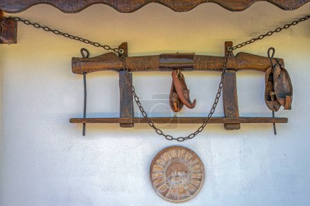 Traditional objects from the old Romanian peasant household as: wooden yoke for oxen, leather shoes called opinci, clay wheel and metal chains, used as external decorative objects on a wall of a house