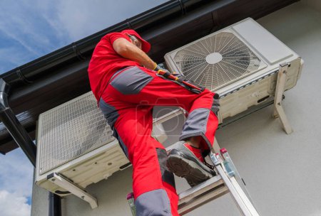 Caucasian Professional Technician Checking Air Conditioner Outdoor Unit During Regular Maintenance Visit. Residential House Climate Control Installation.