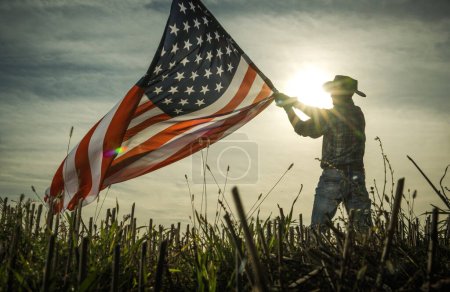 Photo for Man Shows Love of Country by Waving American Flag. Patriotic Cowboy. - Royalty Free Image
