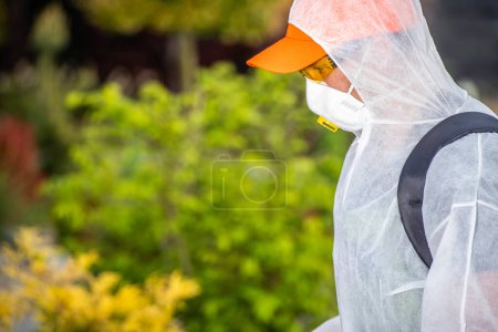 Photo for Professional Gardener in Protective Uniform Performing Pest-Control Chemicals Application. Pesticide Spraying Safety Equipment. - Royalty Free Image