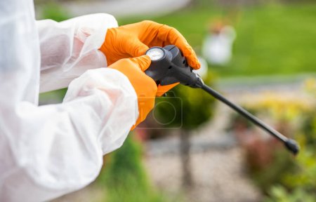 Photo for Professional Gardener in Safety Outfit Calibrating Pesticide Sprayer Before Starting Pest-Control Treatment. Garden Care and Maintenance Theme. - Royalty Free Image