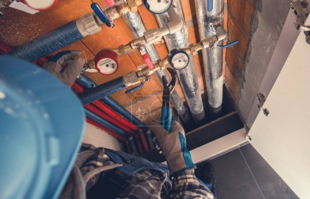 Téléchargez les photos : Aerial View of Plumber with Hydraulic Key Performing Hot and Cold Water Meters Service and Repair. Residential Water Supply Theme. - en image libre de droit
