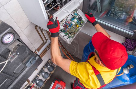 Téléchargez les photos : Professional Caucasian Plumber Repairing Broken Gas Water Heater. Residential Heating System Maintenance. Top View. - en image libre de droit