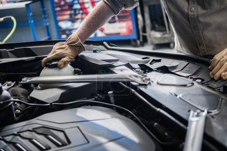 Téléchargez les photos : Car Mechanic Checking On Vehicle Engine Coolant Level Inside Car Service Center. Automotive Theme. - en image libre de droit