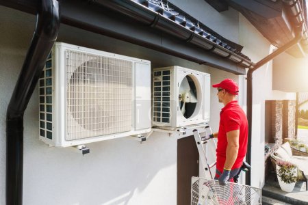 Téléchargez les photos : Caucasian Professional HVAC Technician Performing Air Condition and Heat Pump Units Maintenance. Residential Heating and Cooling Theme. - en image libre de droit