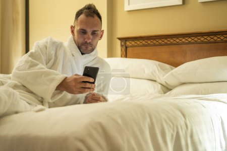 Photo for Caucasian Man Checking His Social Media Profiles Before Going to Sleep Inside a Hotel Room. - Royalty Free Image