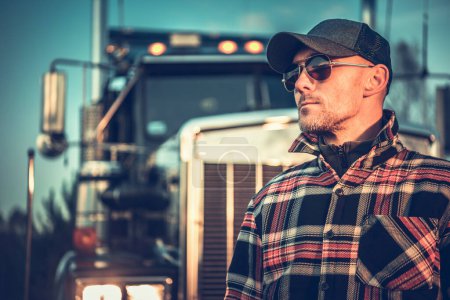 Photo for Proud Semi Truck Driver Portrait in Front of the Vehicle. Caucasian Trucker in His 40s Wearing Baseball Hat. - Royalty Free Image