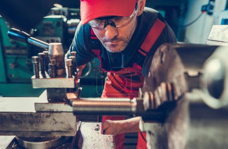 Téléchargez les photos : Caucasian Professional Lathe Machine Operator Wearing Safety Glasses Processing Piece of Metal Element - en image libre de droit