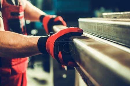 Foto de Metalworking Shop Worker Taking Piece of a Metal Square Tube Close Up Photo. Material For a Welding Job. - Imagen libre de derechos