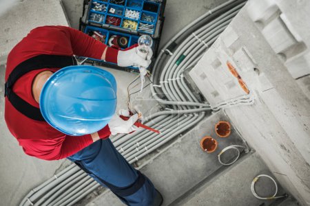 Foto de Top View of Professional Electrician Checking Wires While Performing Electrical Wiring Installation. Industrial Theme. - Imagen libre de derechos