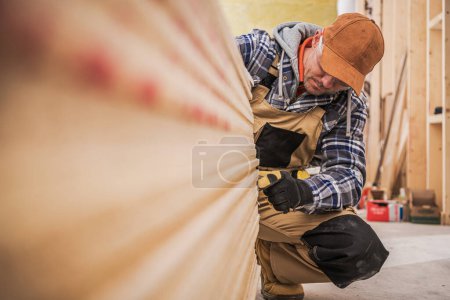 Téléchargez les photos : Caucasien entrepreneur général en construction travailleur dans sa quarantaine compter des morceaux de panneaux de cloisons sèches - en image libre de droit