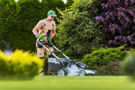 Photo for Professional Gardener Mowing the Lawn with Cordless Battery Powered Electric Mower. Residential Garden Maintenance Theme. - Royalty Free Image