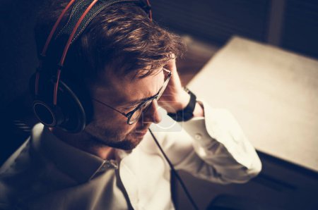 Foto de Caucasian Man in His 30s Listening Audio Book Using Professional Headphones. Quality Audio by Professional Equipment Theme. - Imagen libre de derechos