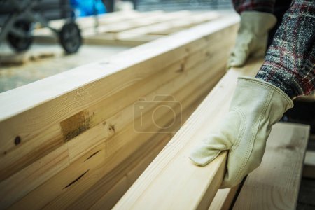 Photo for Woodworker Selecting Wood Beam For His Construction Project. Industrial Theme. - Royalty Free Image