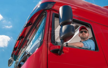 Kaukasischer Euro-Lastwagenfahrer in seinen Dreißigern hinterm Steuer. Thema Bodenverkehr der Europäischen Union.