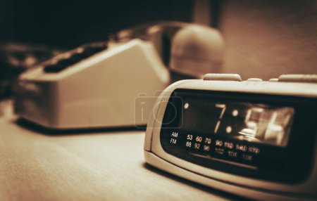 Photo for Vintage Hotel Room alarm Clock and the Analog Phone Close Up. Sepia Color Grading. - Royalty Free Image