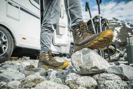 Photo for Preparing Right Hiking Shoes For a Mountain Trail. Tourist Staying Next to His Camper Van RV Getting Ready For a Hike. - Royalty Free Image
