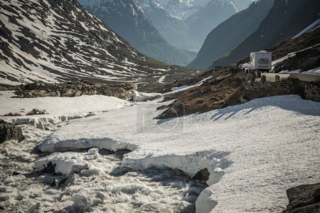 Téléchargez les photos : RV blanc conduisant le long d'une route dans la vallée enneigée de montagne norvégienne. Motorhome thème de voyage. - en image libre de droit