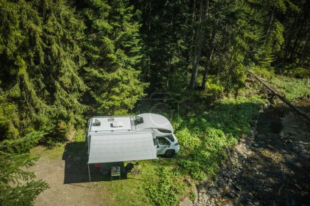 Foto de Vista aérea de White Camper Van Estacionado Solo en el Bosque Junto a Woodland Stream. RV Camping y Viajar Tema. - Imagen libre de derechos
