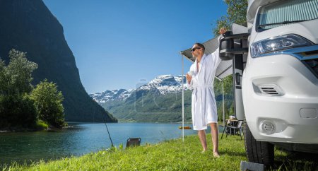 Kaukasischer Tourist im Urlaub mit einer Tasse Kaffee vor seinem Wohnmobil im malerischen norwegischen Ort.