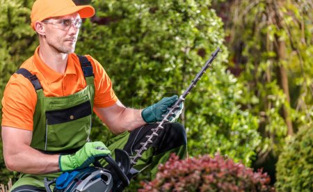 Téléchargez les photos : Jardinier professionnel avec sa tondeuse à arbustes puissante. Équipement de jardinage thème. - en image libre de droit