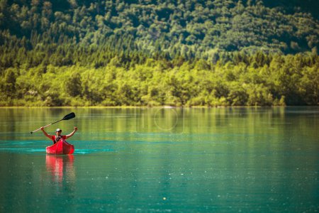 Téléchargez les photos : Joyeux voyageur à l'intérieur du canot rouge sur un lac glaciaire avec les mains en l'air - en image libre de droit