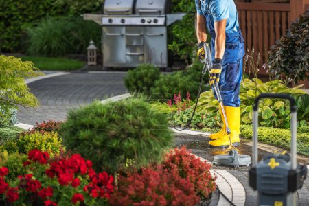 Caucasian Homeowner Pressure Washing His Backyard Garden Bricks Made Paths