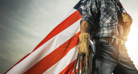 Téléchargez les photos : Photo conceptuelle de la main-d'œuvre de l'Ouest américain avec Rancher et drapeau national américain - en image libre de droit