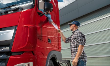Téléchargez les photos : Conducteur de semi-camion recevant la documentation de fret tout en restant dans sa cabine de camion - en image libre de droit