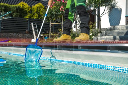 Photo for Poolside Maintenance Worker Cleaning Water Surface with a Net. Keeping Swimming Pool Clean. - Royalty Free Image