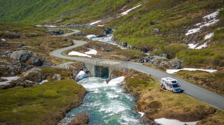 Norwegian Scenic Mountain Road y Camper Van Next to the River. Tema al aire libre y recreación.