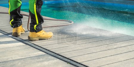 Photo for Man Cleaning His Poolside Deck with a Water. Swimming Pool Area Maintenance. - Royalty Free Image