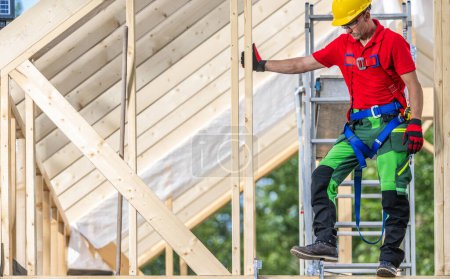 Téléchargez les photos : Entrepreneur professionnel en bois de cadre de squelette sur un niveau de grenier d'une maison nouvellement développée - en image libre de droit