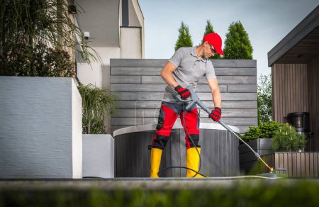 Photo for Caucasian Homeowner in His 40s Cleaning Patio Concrete Bricks Using Pressure Washer - Royalty Free Image