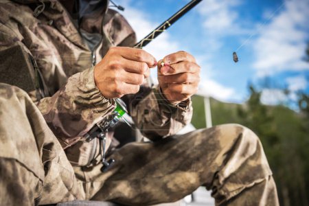 Téléchargez les photos : Blanc pêcheur préparation poisson appât sur son bâton de pêche Gros plan - en image libre de droit