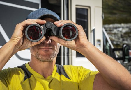 Photo for Caucasian Tourist in His 40s Spotting Wildlife Using Binoculars While Staying in Front of His RV Camper Van - Royalty Free Image