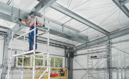 Foto de Trabajador profesional de HVAC en un andamio que instala el conducto de aire - Imagen libre de derechos