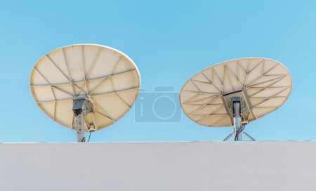 Téléchargez les photos : Deux plats satellites sur le toit contre ciel bleu clair. Thème technologique. - en image libre de droit