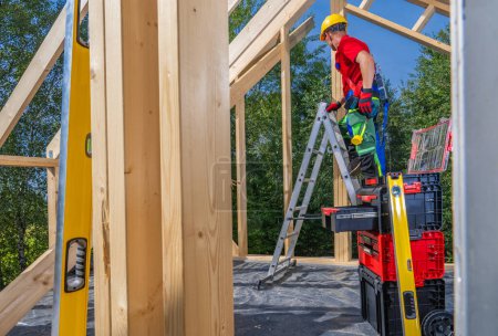 Téléchargez les photos : Travailleur contractuel de construction caucasien dans sa quarantaine travaillant sur ossature de maison en bois - en image libre de droit