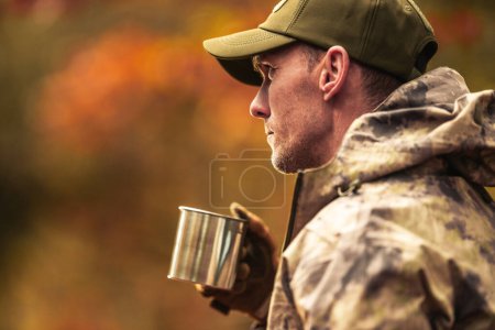 Foto de Cazador caucásico de 40 años usando camuflaje bebiendo un café. Tema de temporada de caza. - Imagen libre de derechos