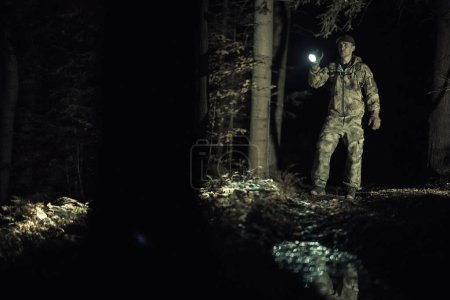 Téléchargez les photos : Chercher un membre d'équipage avec une lampe de poche à la recherche d'une personne disparue dans un boisé sombre - en image libre de droit